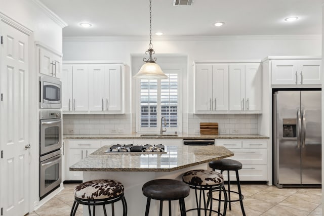 kitchen with sink, appliances with stainless steel finishes, a center island, light stone countertops, and white cabinets