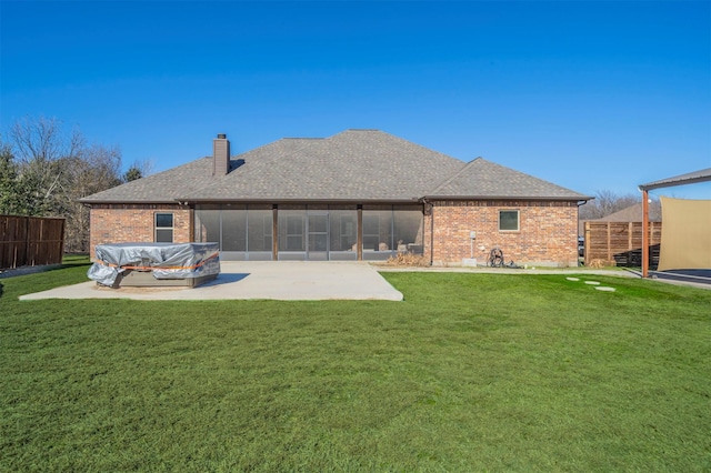 rear view of property with a yard, a patio area, and a sunroom