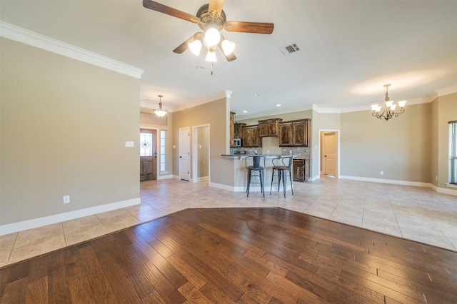 unfurnished living room with ornamental molding, ceiling fan with notable chandelier, and light hardwood / wood-style flooring