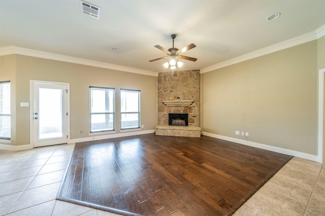 unfurnished living room with ornamental molding, a stone fireplace, hardwood / wood-style floors, and ceiling fan