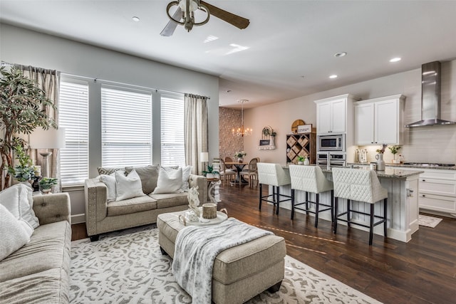 living room featuring ceiling fan with notable chandelier and dark wood-type flooring