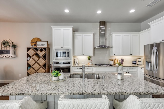 kitchen with stainless steel appliances, a breakfast bar, a large island with sink, and wall chimney exhaust hood