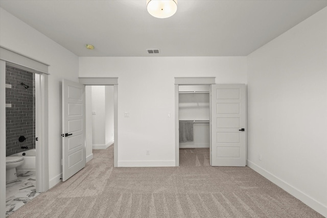 unfurnished bedroom featuring a walk in closet, connected bathroom, light carpet, and a closet