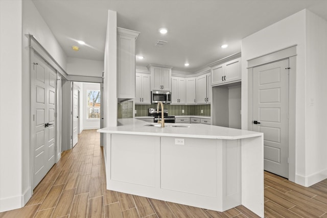 kitchen with tasteful backsplash, stainless steel appliances, sink, and white cabinets