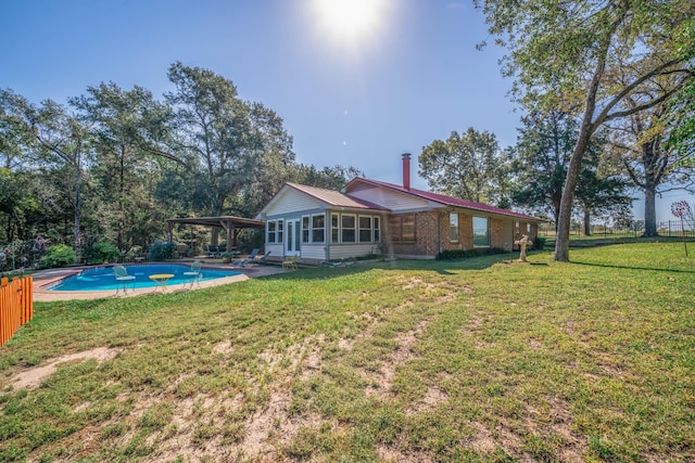 rear view of property featuring a lawn and a sunroom