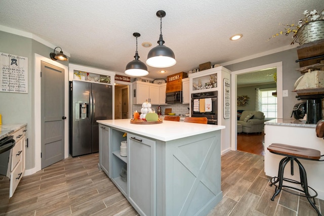 kitchen with a kitchen island, decorative light fixtures, white cabinetry, decorative backsplash, and black appliances