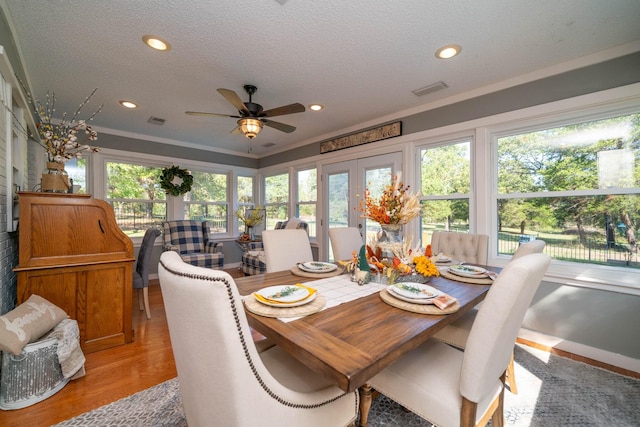 dining area with french doors, ornamental molding, a textured ceiling, and light wood-type flooring