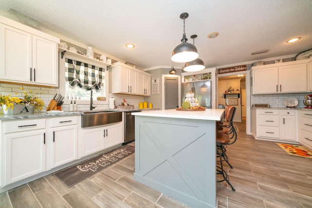 kitchen with stainless steel appliances, hanging light fixtures, a kitchen island, and white cabinets