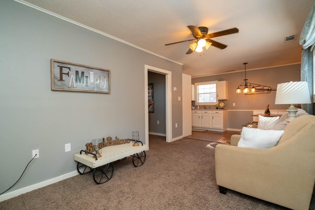 living room with sink, ceiling fan with notable chandelier, ornamental molding, and carpet flooring