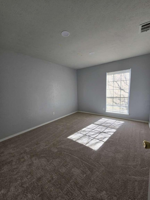 carpeted spare room with a textured ceiling