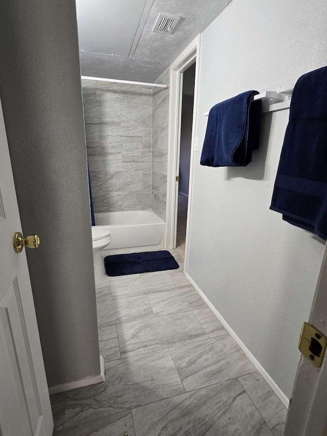 bathroom with tiled shower / bath, toilet, and a textured ceiling