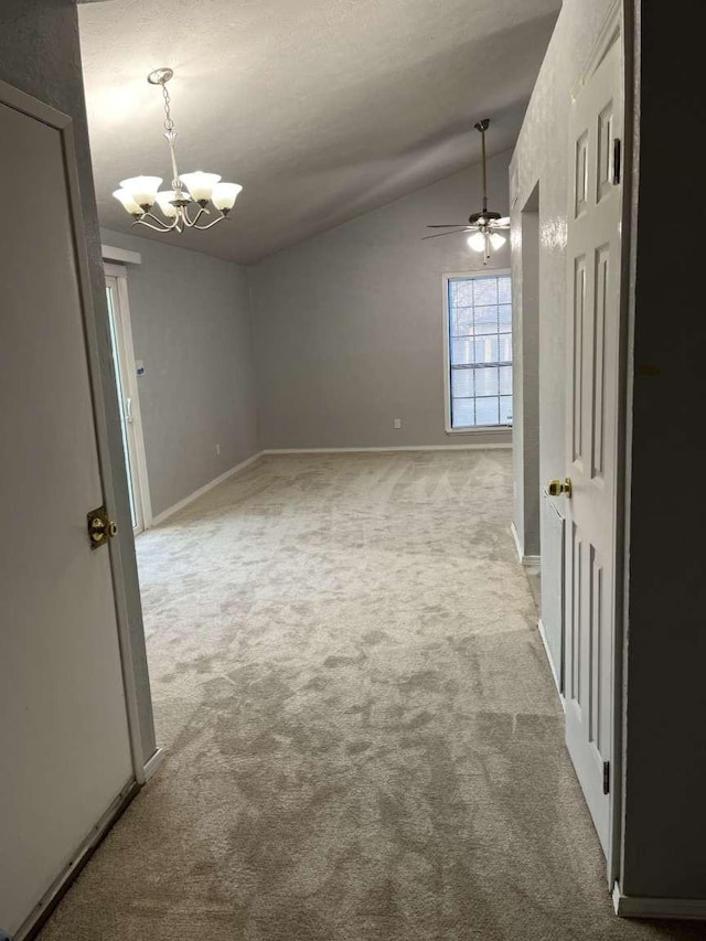 empty room with light colored carpet, lofted ceiling, and ceiling fan with notable chandelier