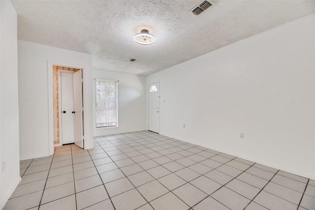 tiled empty room featuring a textured ceiling