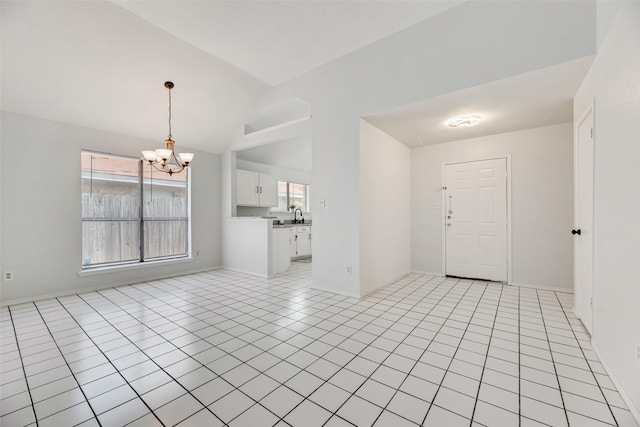 entrance foyer with light tile patterned flooring, lofted ceiling, a chandelier, and sink