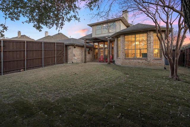 back house at dusk featuring a yard and a patio area