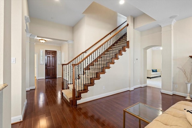 entrance foyer with ornamental molding, dark wood-type flooring, and decorative columns