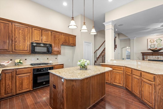 kitchen featuring ornate columns, tasteful backsplash, light stone counters, decorative light fixtures, and black appliances