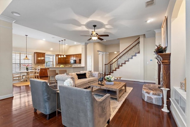 living room with ornate columns, ceiling fan, and dark hardwood / wood-style flooring