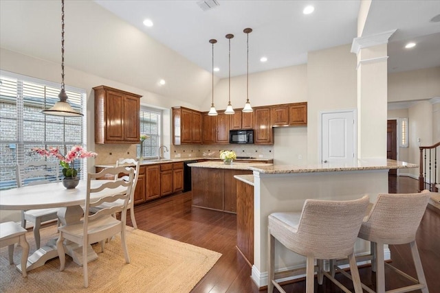 kitchen featuring hanging light fixtures, a towering ceiling, light stone countertops, and a kitchen island