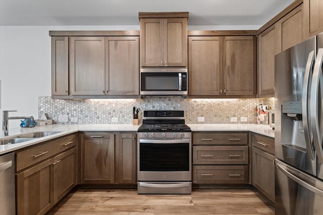 kitchen featuring sink, backsplash, light hardwood / wood-style flooring, and appliances with stainless steel finishes