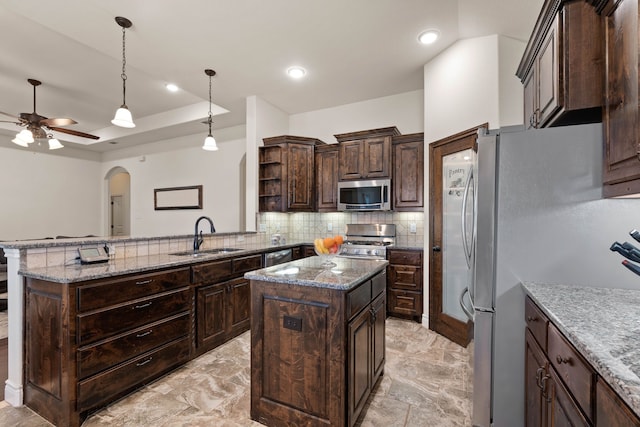 kitchen featuring appliances with stainless steel finishes, sink, a center island, dark brown cabinetry, and kitchen peninsula