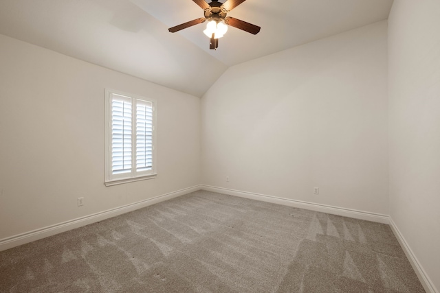 carpeted spare room featuring vaulted ceiling and ceiling fan