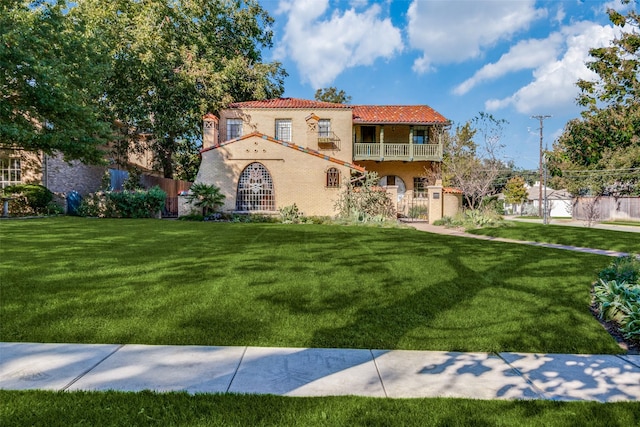 mediterranean / spanish home with a front yard and a balcony