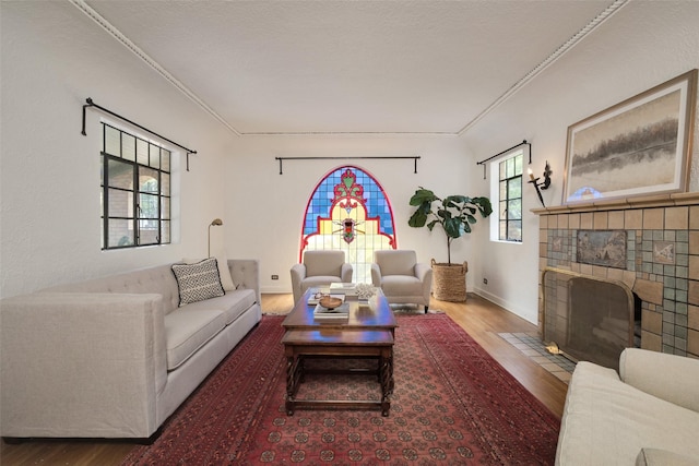 living room featuring hardwood / wood-style floors, ornamental molding, and a tile fireplace