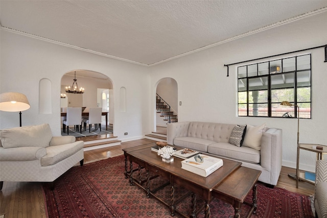 living room with ornamental molding, hardwood / wood-style floors, a textured ceiling, and a notable chandelier