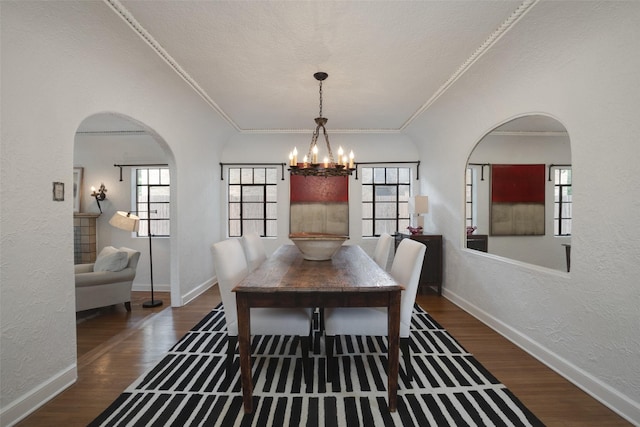 dining room featuring ornamental molding, plenty of natural light, dark wood-type flooring, and an inviting chandelier