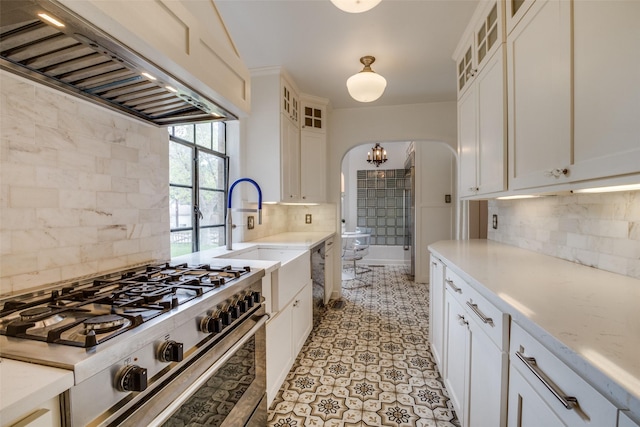 kitchen featuring white cabinets, premium range hood, stainless steel range, and backsplash