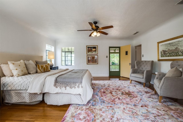 bedroom with hardwood / wood-style floors, access to outside, and ceiling fan