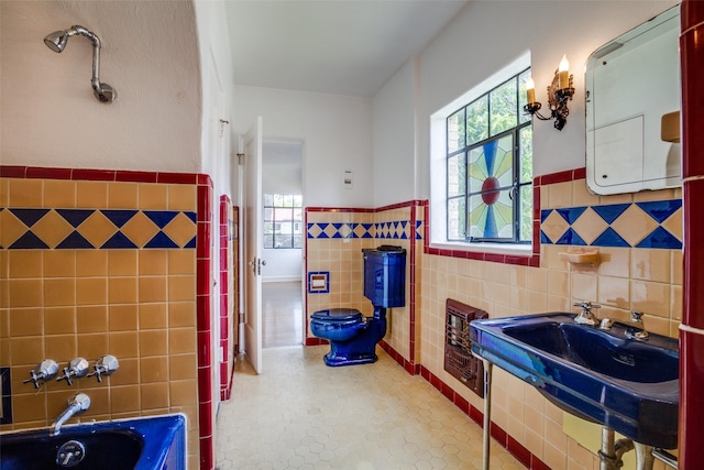 bathroom with tile walls, a bath, tile patterned flooring, and sink