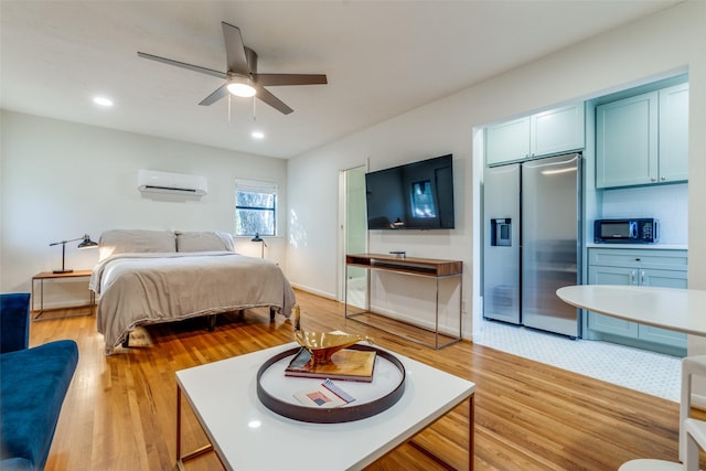 bedroom with stainless steel refrigerator with ice dispenser, ceiling fan, a wall mounted AC, and light wood-type flooring