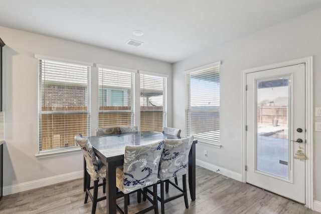 dining area with light wood finished floors, visible vents, and baseboards