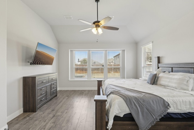 bedroom featuring visible vents, baseboards, vaulted ceiling, and wood finished floors