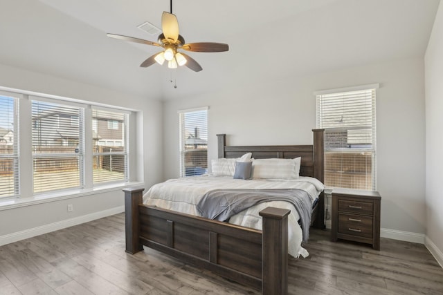 bedroom with a ceiling fan, visible vents, baseboards, and wood finished floors