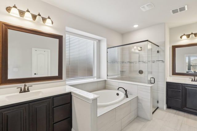 full bathroom with two vanities, plenty of natural light, visible vents, and a sink