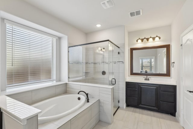 bathroom featuring vanity, a stall shower, a garden tub, and visible vents