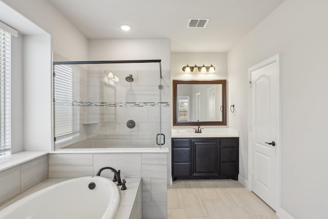 full bathroom with visible vents, a garden tub, vanity, and a shower stall