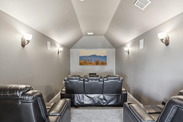 carpeted cinema featuring visible vents and vaulted ceiling