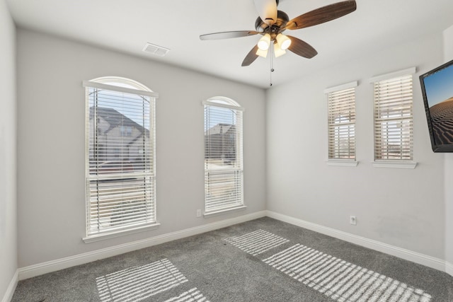 empty room featuring carpet floors, visible vents, ceiling fan, and baseboards