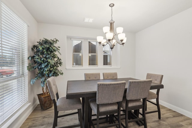 dining space featuring a notable chandelier, visible vents, baseboards, and wood finished floors