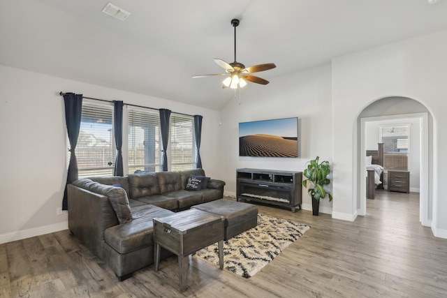 living room with visible vents, arched walkways, vaulted ceiling, and wood finished floors