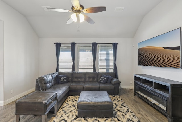 living area with lofted ceiling, ceiling fan, wood finished floors, and baseboards