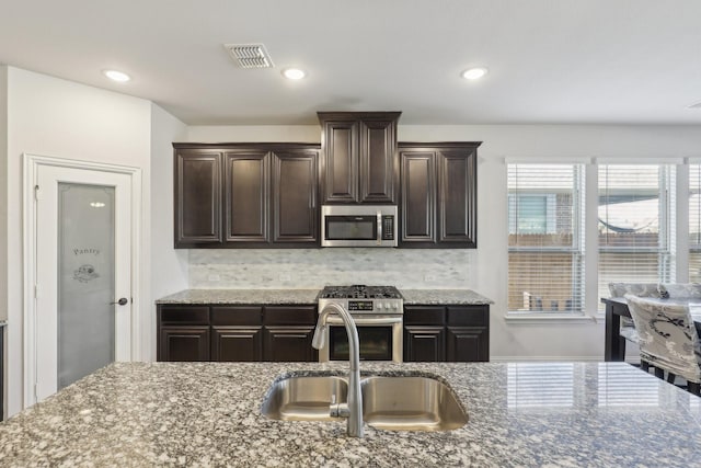 kitchen with stainless steel appliances, a sink, visible vents, and dark brown cabinetry