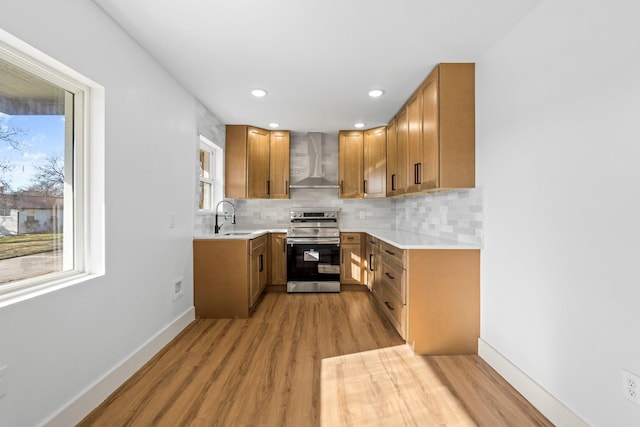 kitchen with sink, stainless steel range with electric cooktop, tasteful backsplash, a healthy amount of sunlight, and wall chimney range hood