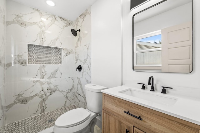 bathroom featuring vanity, toilet, and a tile shower