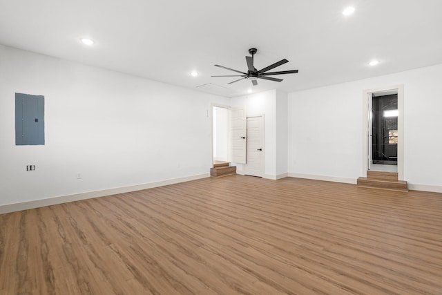 empty room with electric panel, ceiling fan, and light hardwood / wood-style flooring