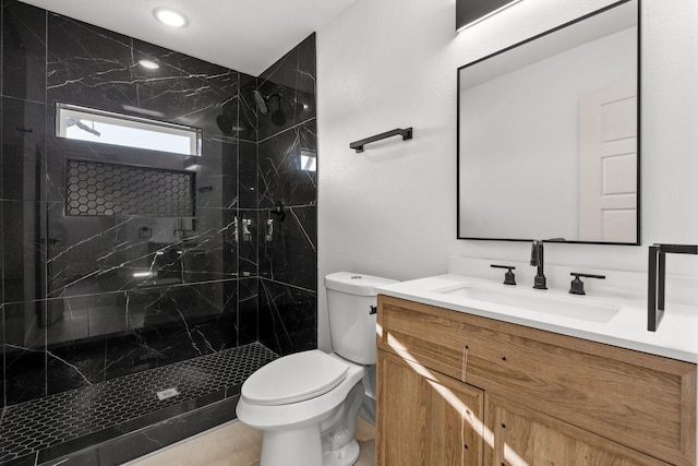 bathroom with vanity, toilet, and a tile shower